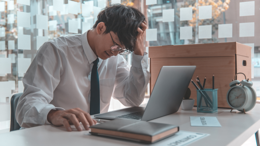 a person sitting at a desk with their head in their hands