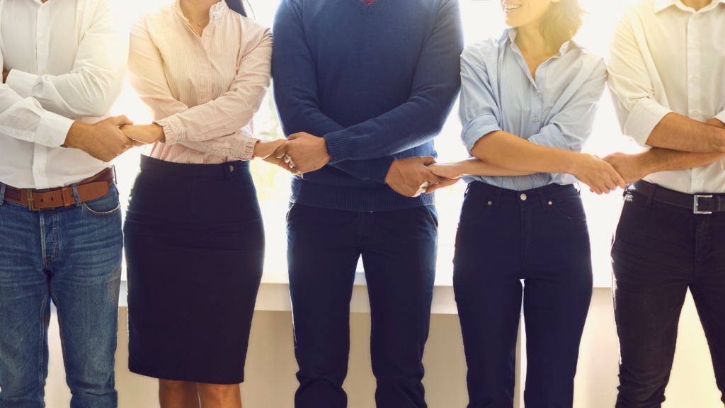 Office employees standing in a row holding hands