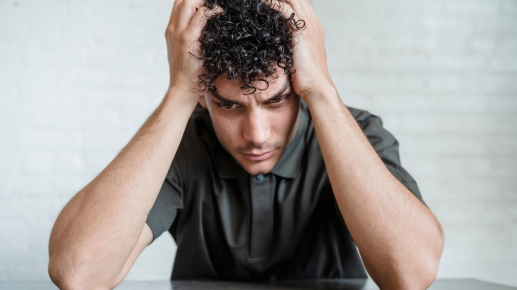 a person sitting at a table with their hands on their head