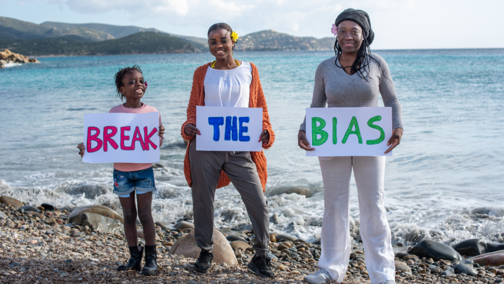 three individuals holding signs that say break the bias