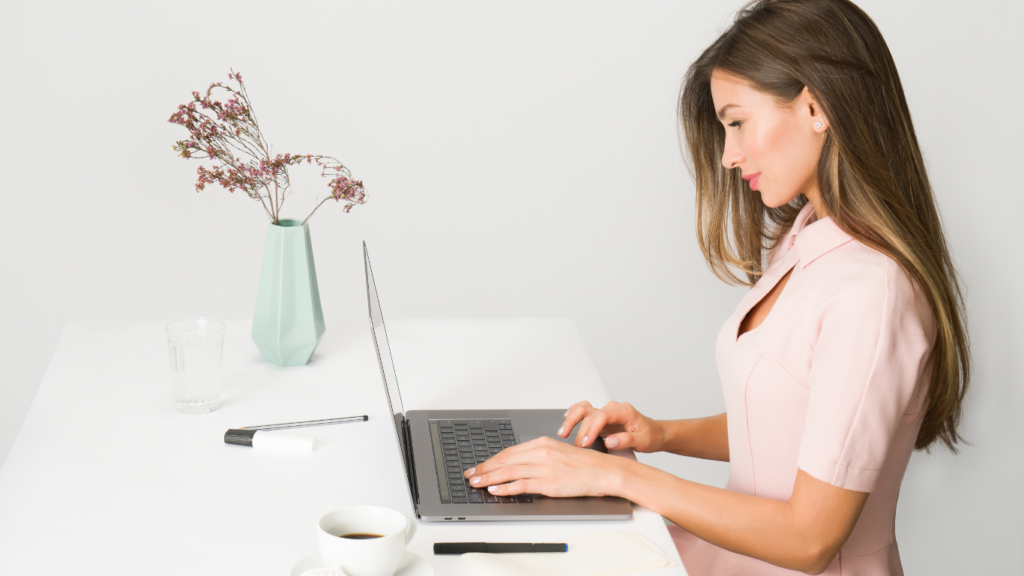 a person is typing on a laptop while sitting at a desk