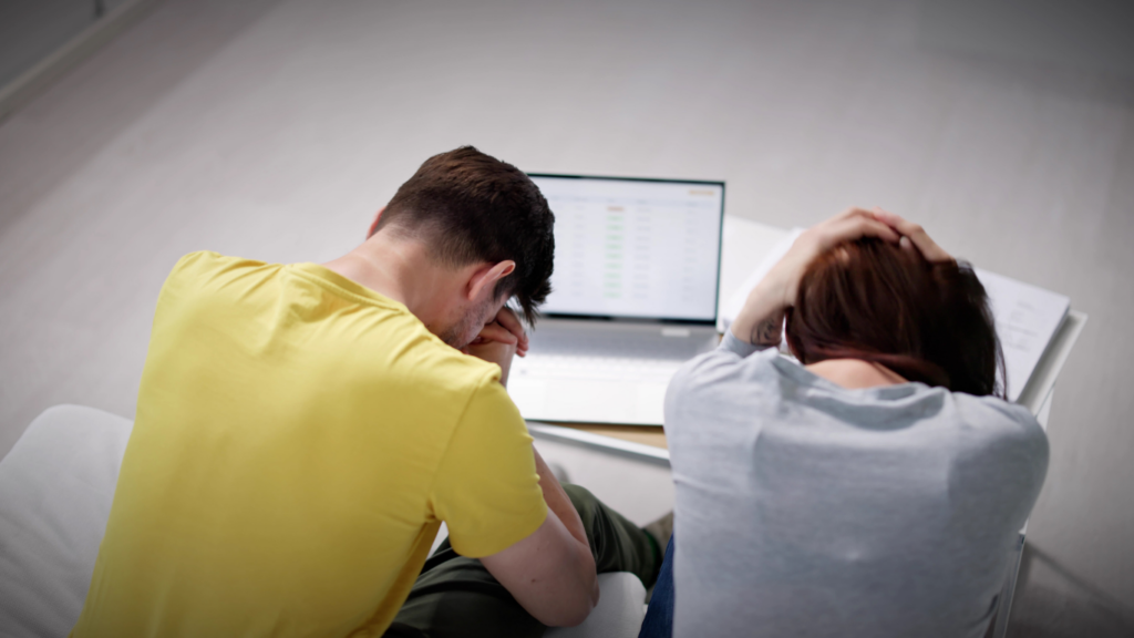 a person sitting in front of a laptop with their hands on their head