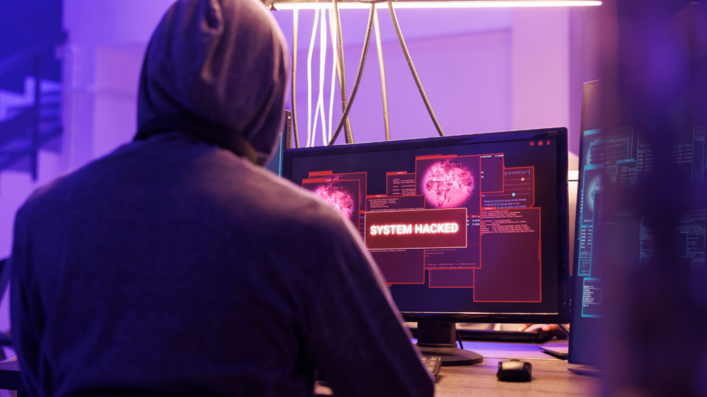 a person wearing a hoodie is sitting in front of three computer screens