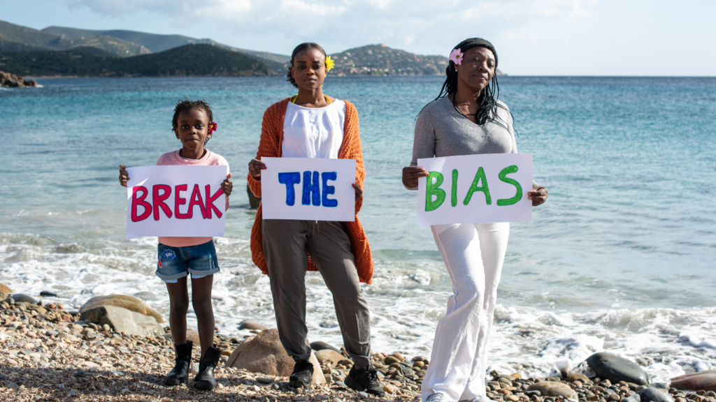 three individuals holding signs that say break the bias